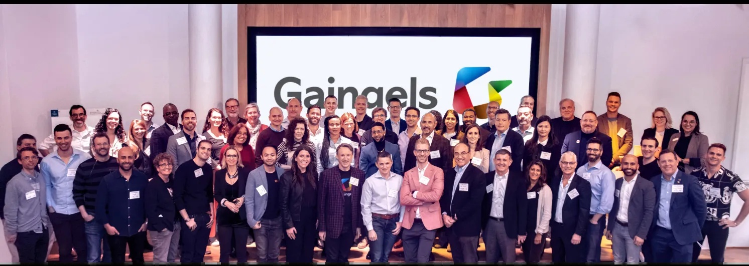 Members of the Gaingels community gathered for a group photograph in front of the organization’s logo.