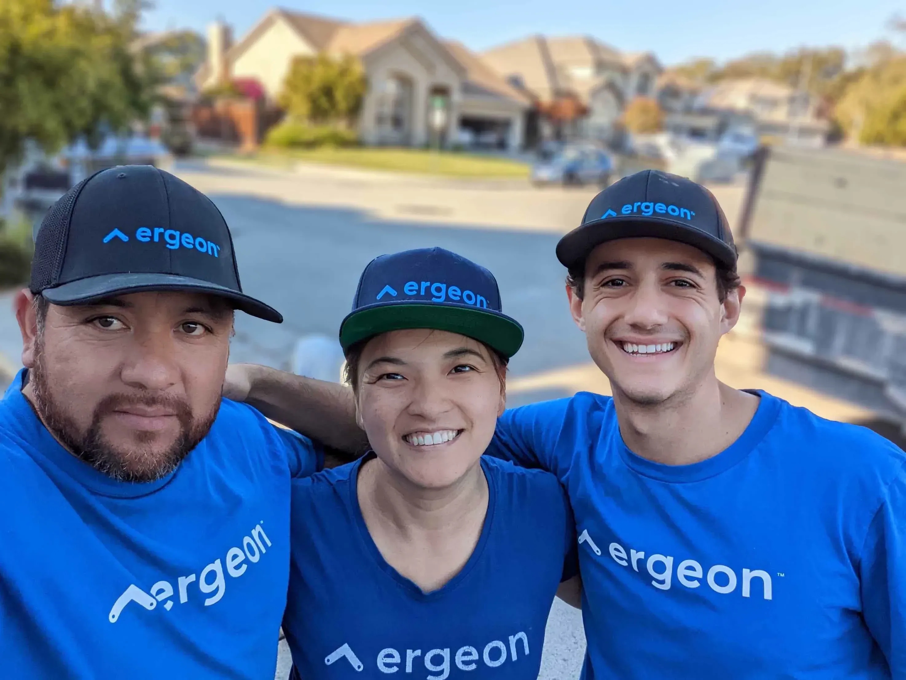 Jenny He, center, with two Ergeon team members outdoors in matching blue shirts and caps