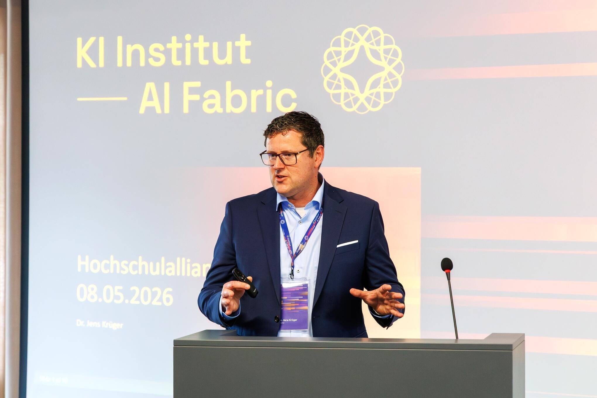 Jens Kruger speaking at a lectern at the AI Fabric institute event in Plauen