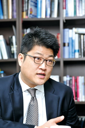 Jeong Hee Kim speaking during an interview in front of bookshelves