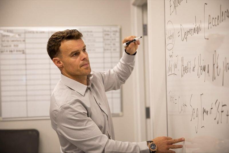 Jeremiah Boucher writing real estate fund calculations on an office whiteboard