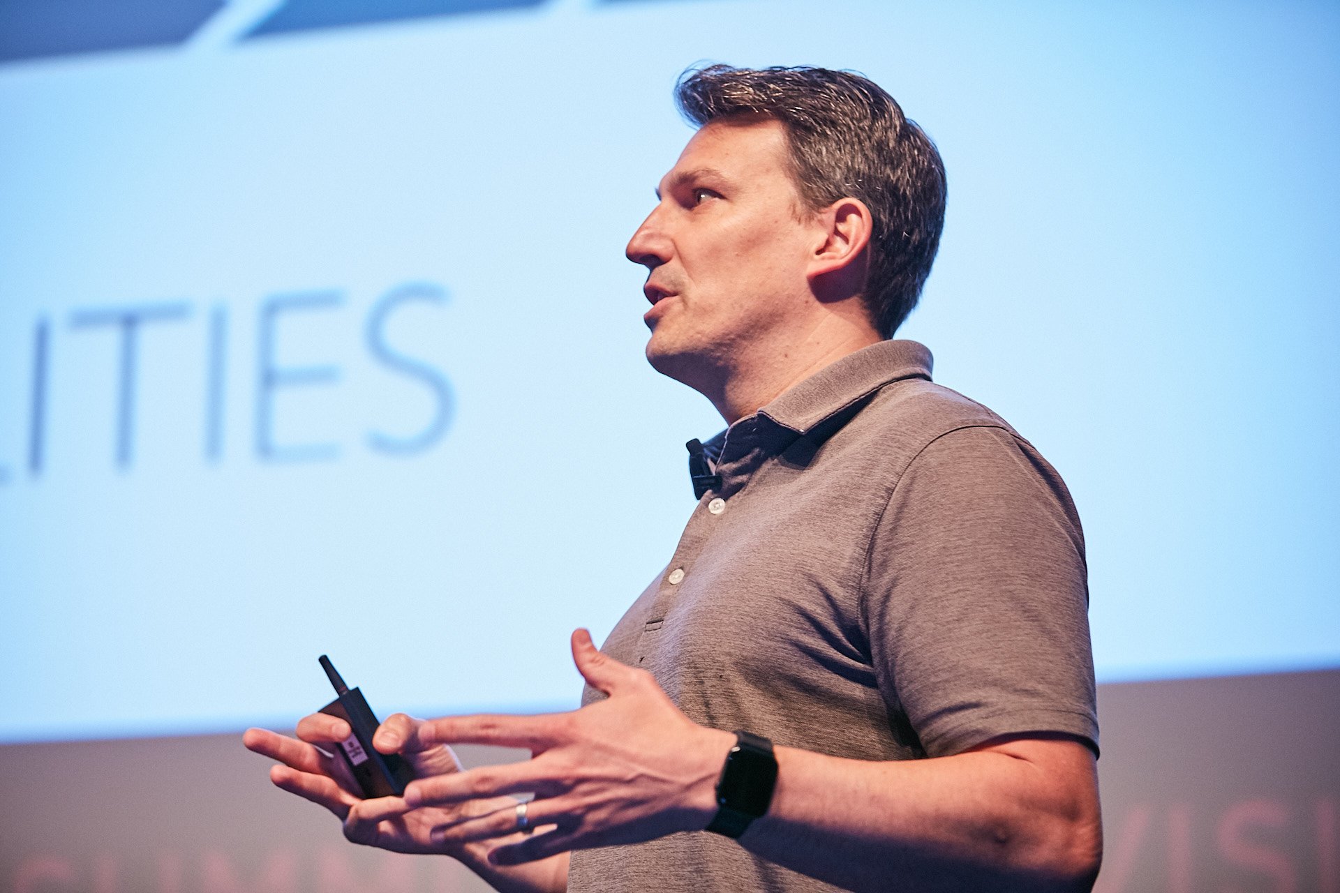 Jeremiah Robison speaking onstage, holding a presentation remote and gesturing