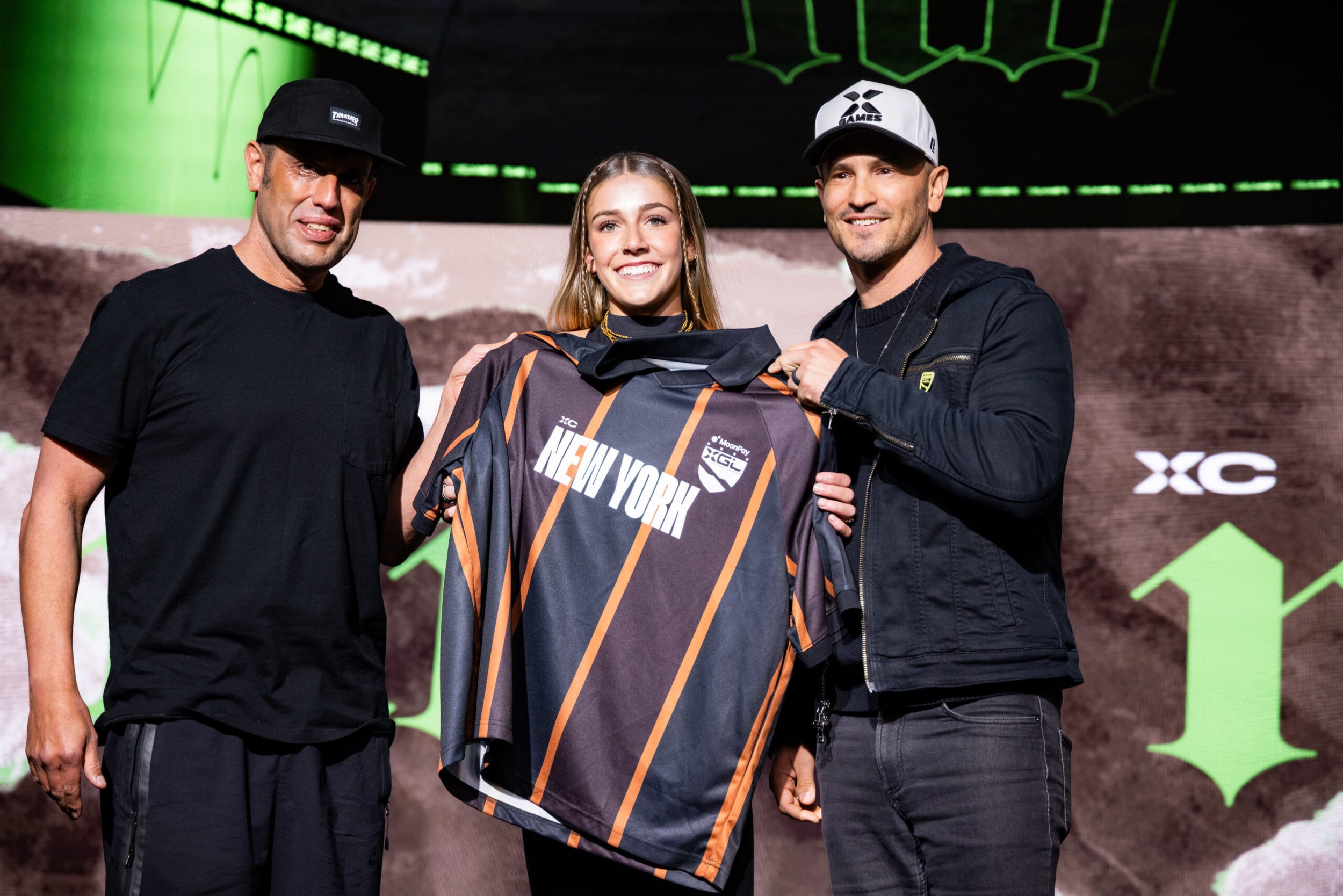 Chloe Covell holding an XC New York jersey beside Steve Rodriguez and Jeremy Bloom at the 2026 summer draft