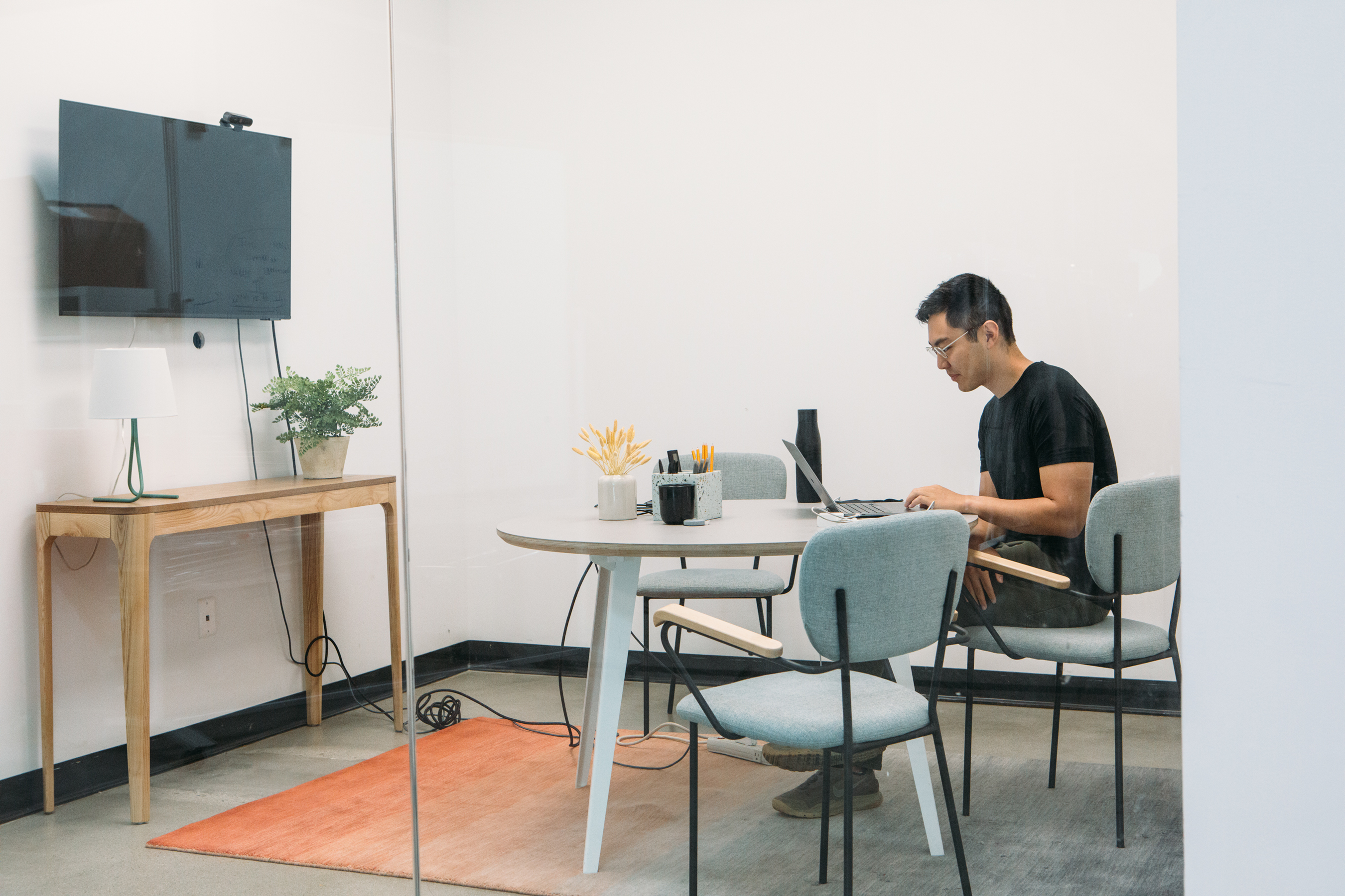 Jeremy Cai working on a laptop at a round table in an office