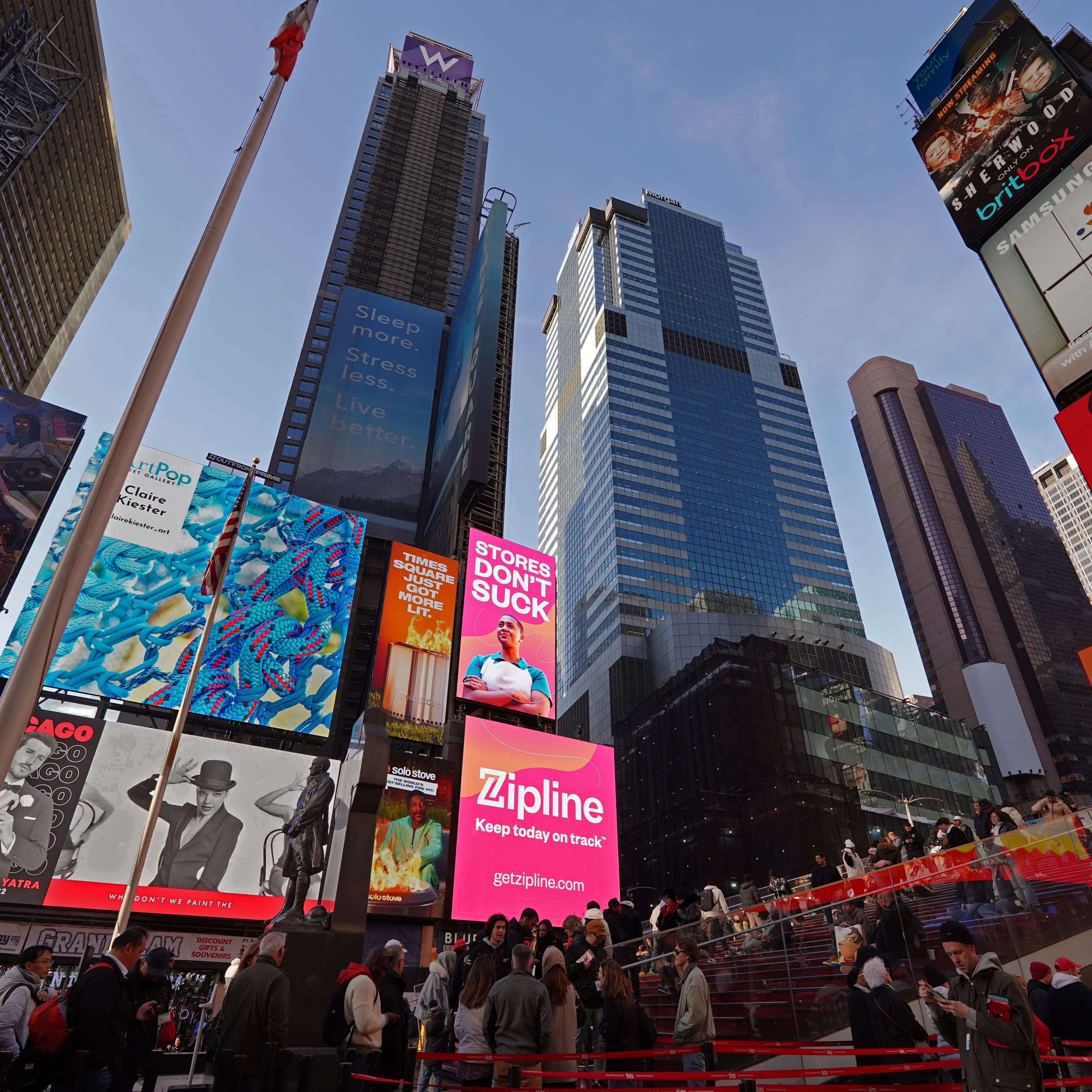 Zipline's pink Stores Don't Suck billboard glowing above Times Square during Black Friday 2024