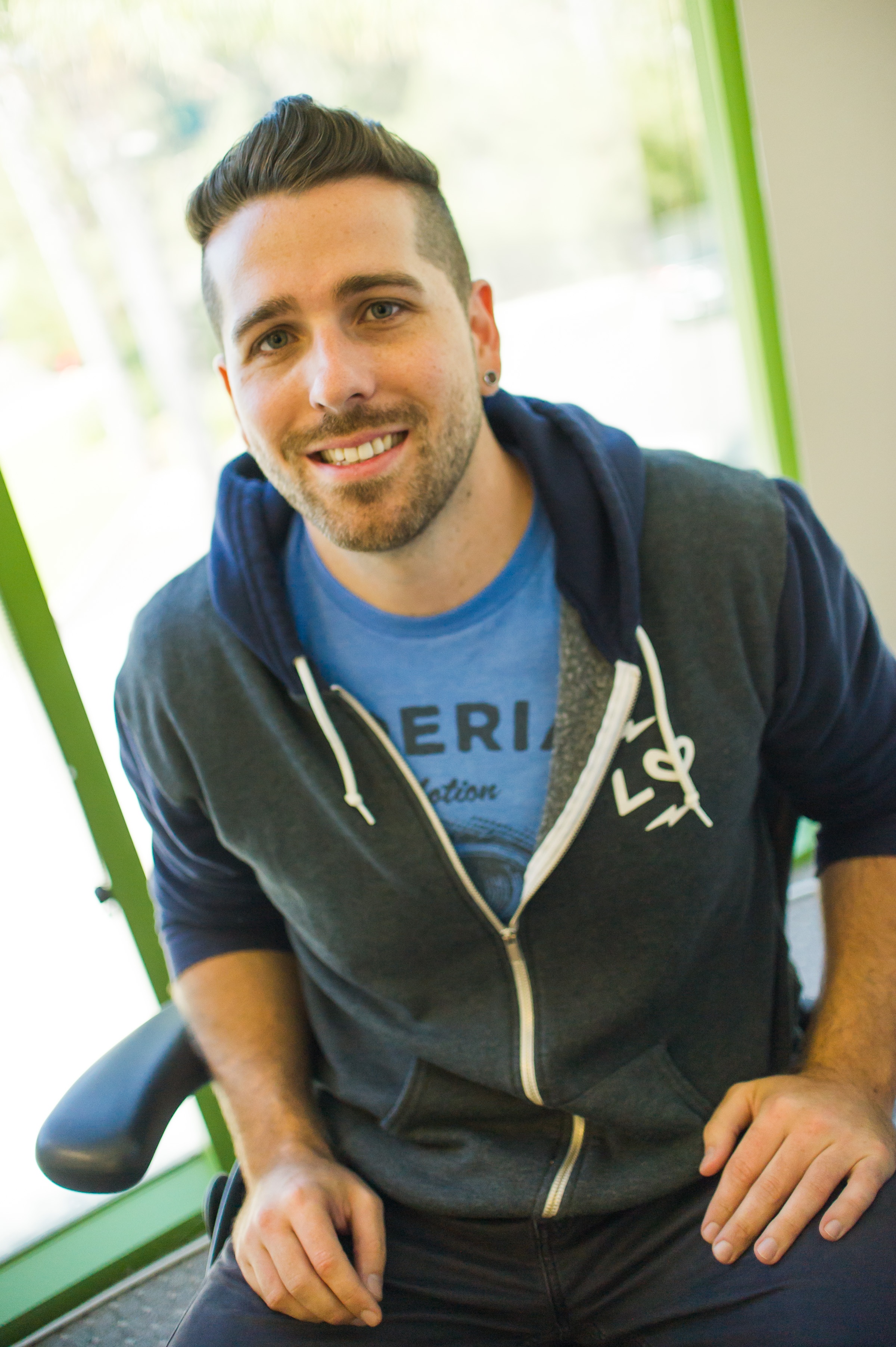 Jeremy Yamaguchi seated in the Lawn Love office wearing a branded hoodie