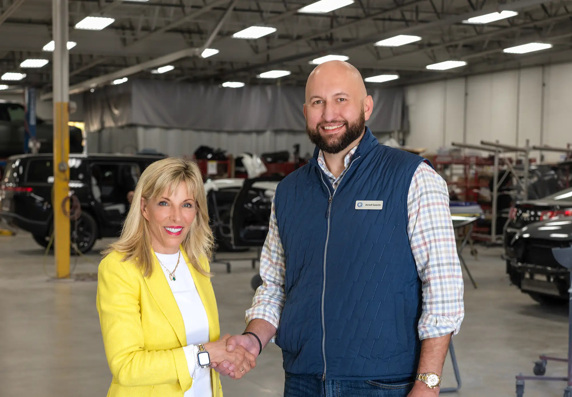 Joanne LaMettry and Jerod Guerin shake hands inside a collision repair facility