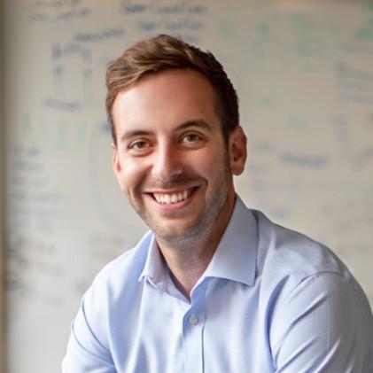 Jesse Comart seated in front of a whiteboard