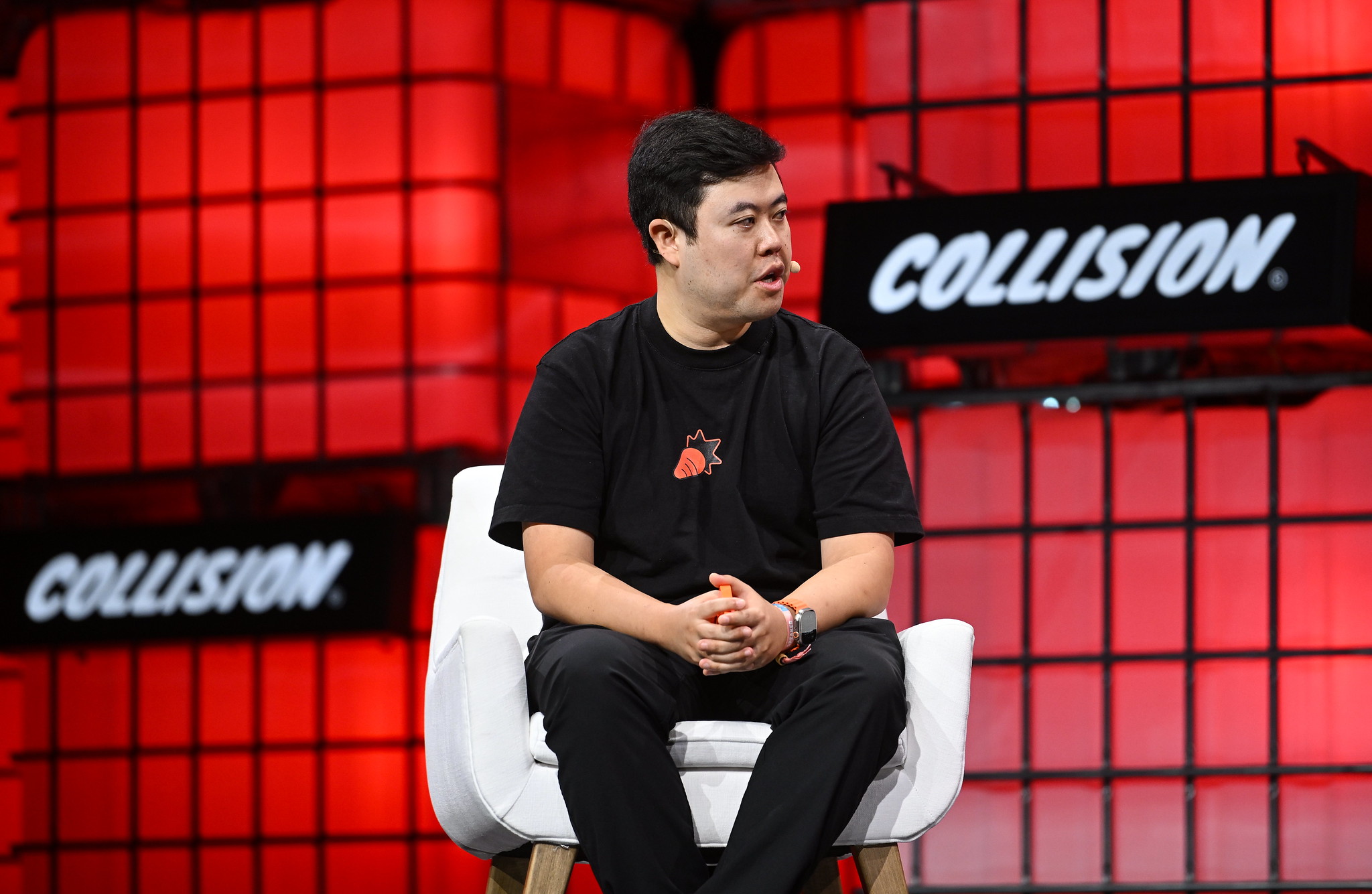 Jesse Lyu speaking on Centre Stage at Collision 2024 in Toronto, holding an orange rabbit r1
