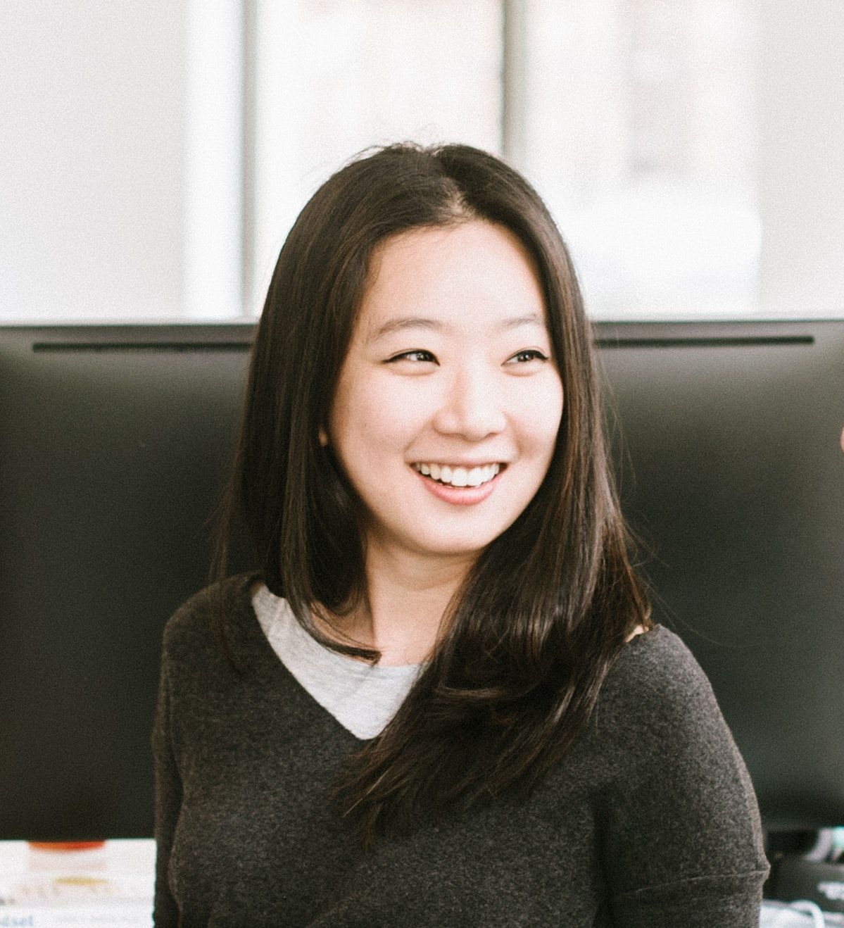 Jessica Ko smiling in a bright office with a large monitor behind her