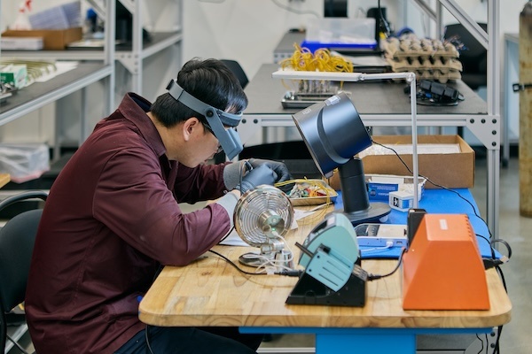 A Jet Parts Engineering technician inspecting and repairing an aircraft component at a workbench