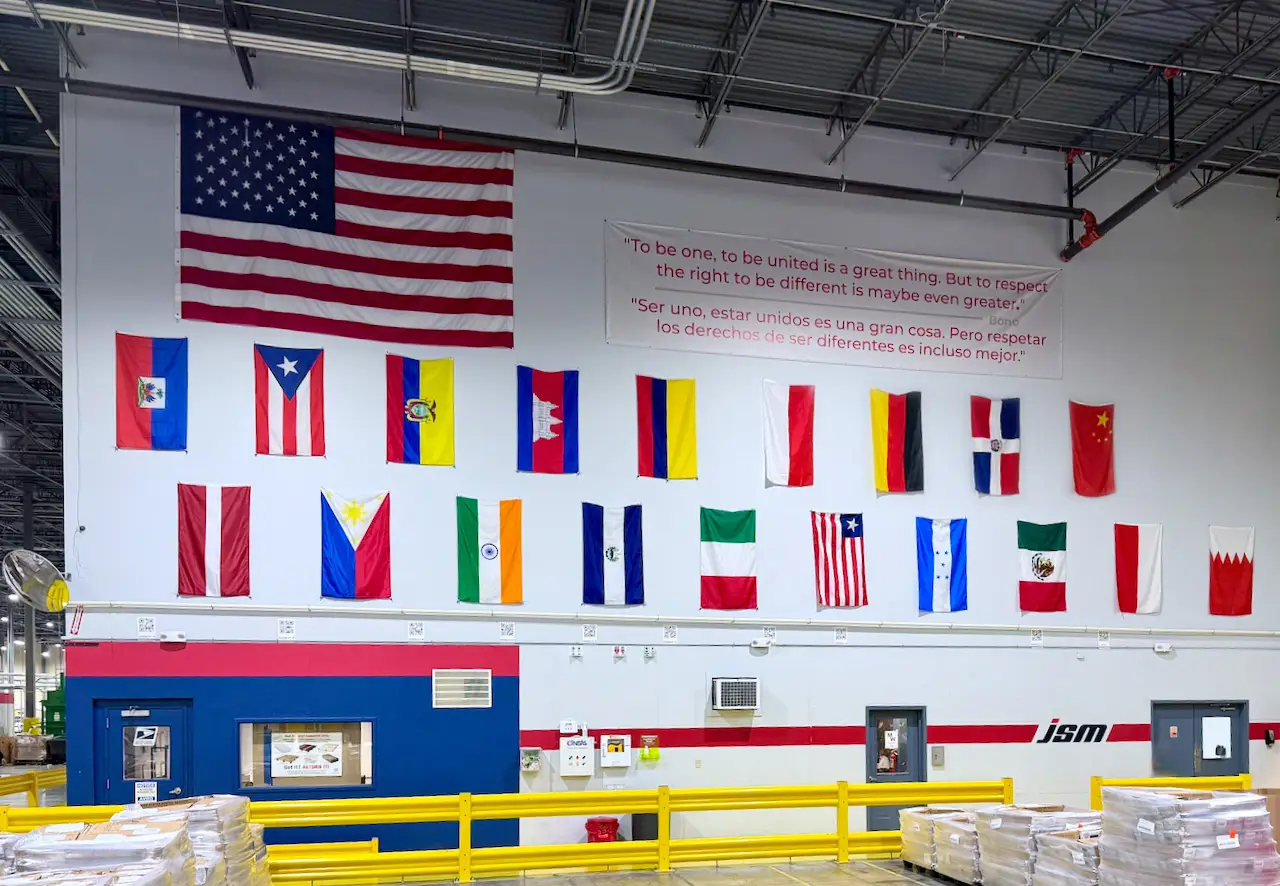 National flags and a bilingual message displayed above JSM’s factory floor
