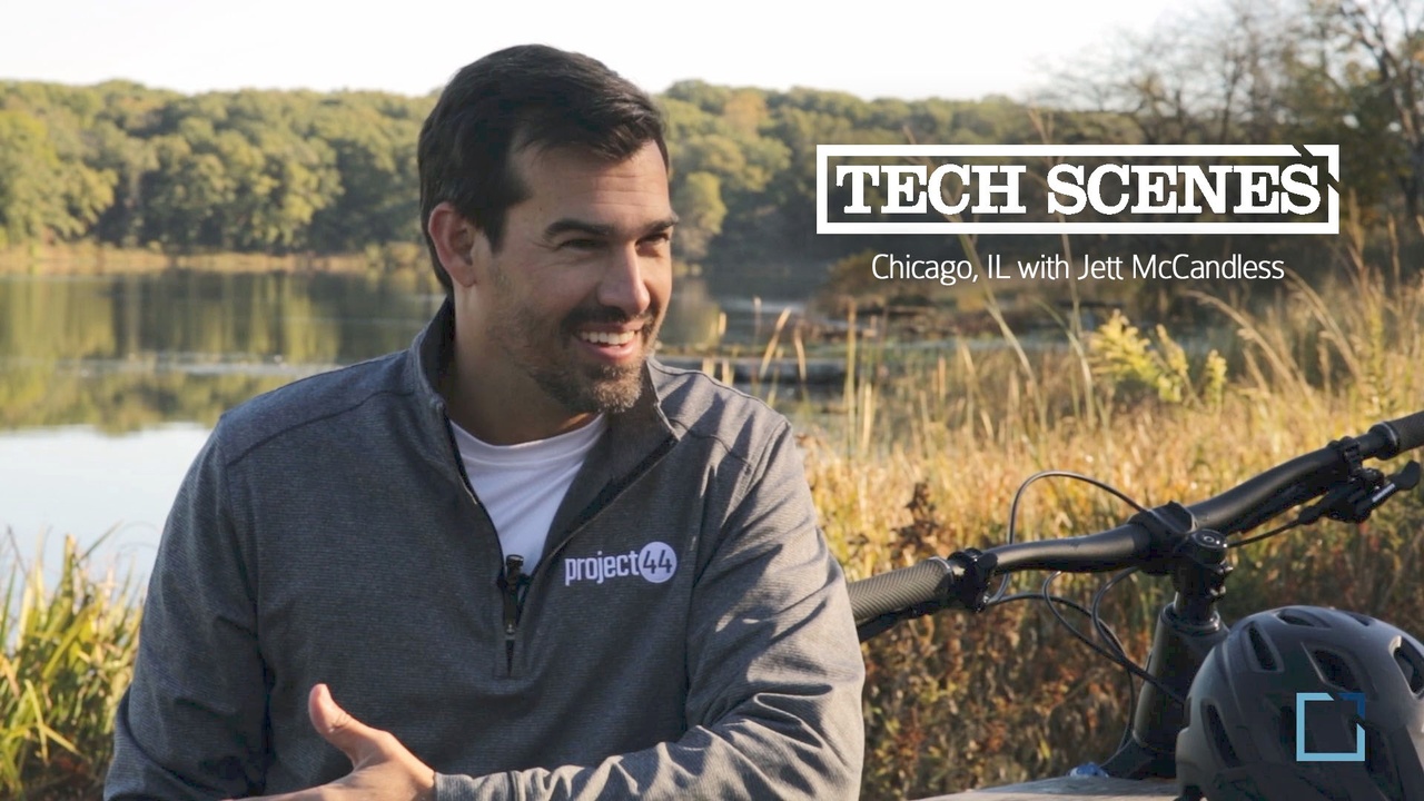 Jett McCandless smiling during an outdoor Tech Scenes interview beside a bicycle and lake