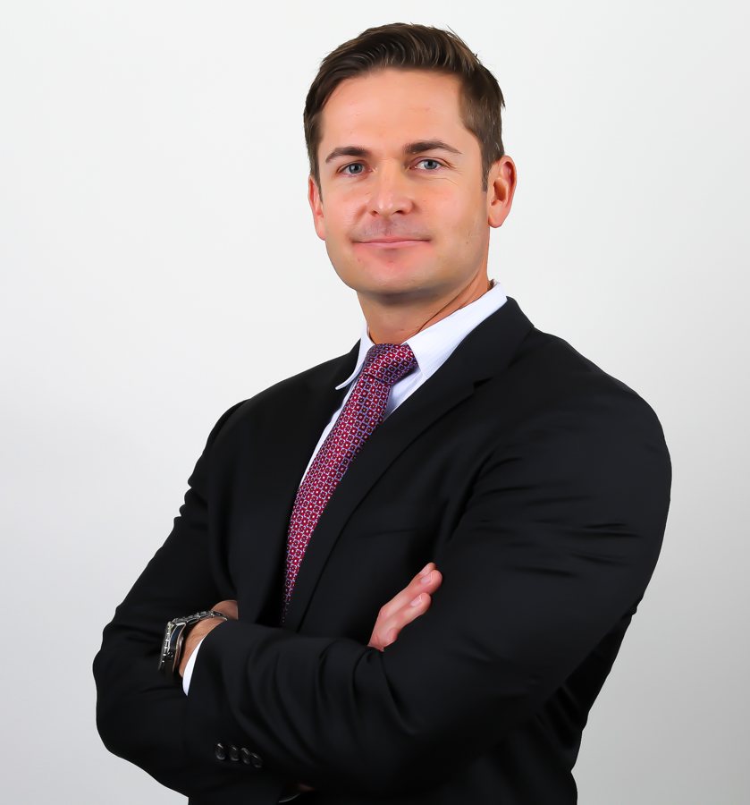 An archival portrait of Jevin Sackett wearing a dark suit and patterned tie