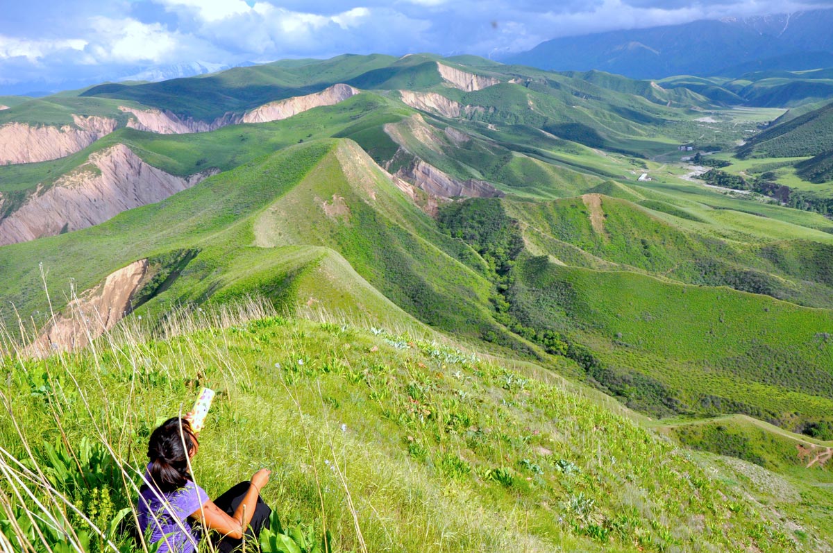 Green hills in Kyrgyzstan with Jia Tolentino seated in the foreground