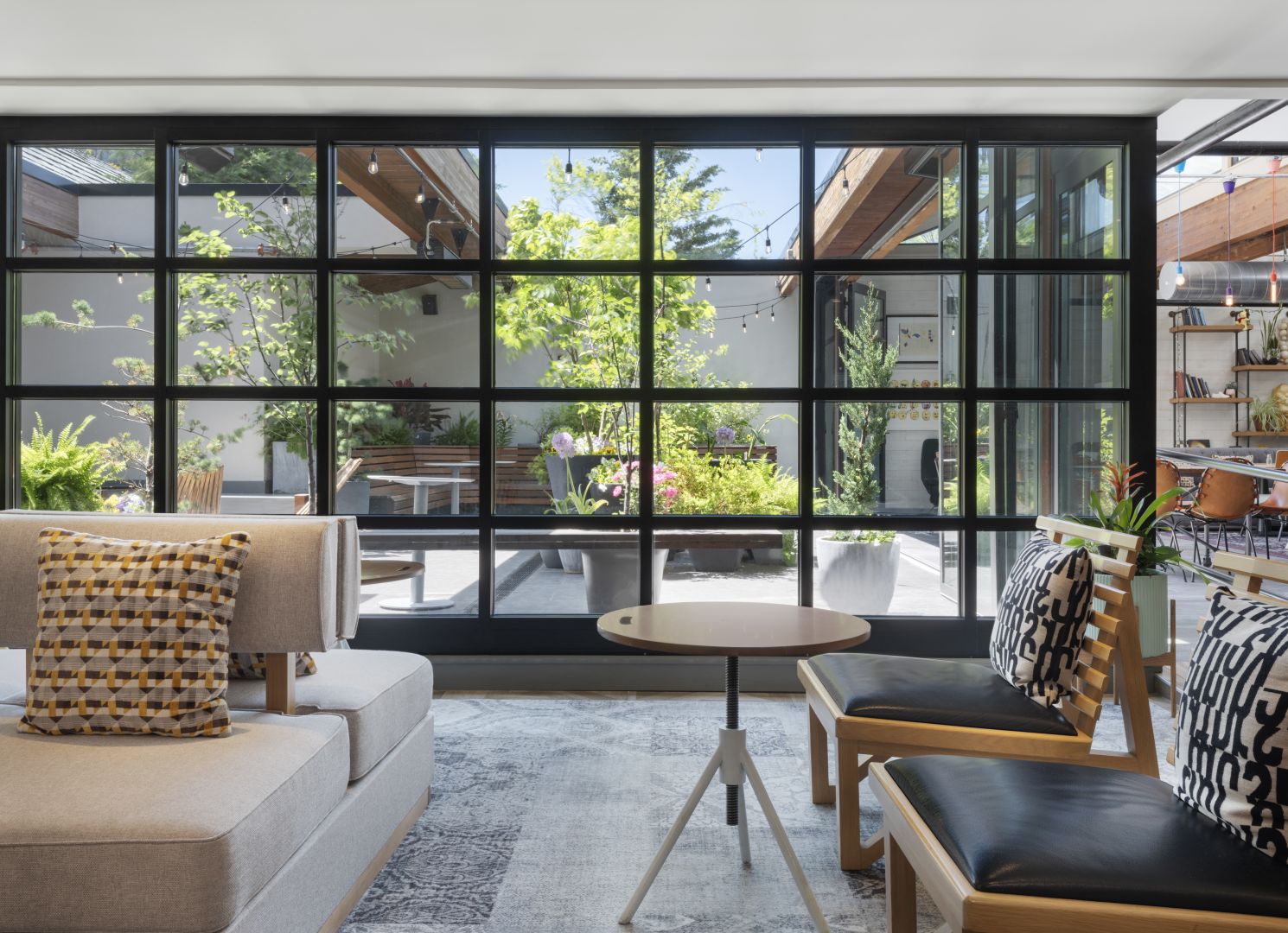 Hotel seating area with patterned cushions and glass doors looking onto a planted courtyard, from JNR’s property gallery