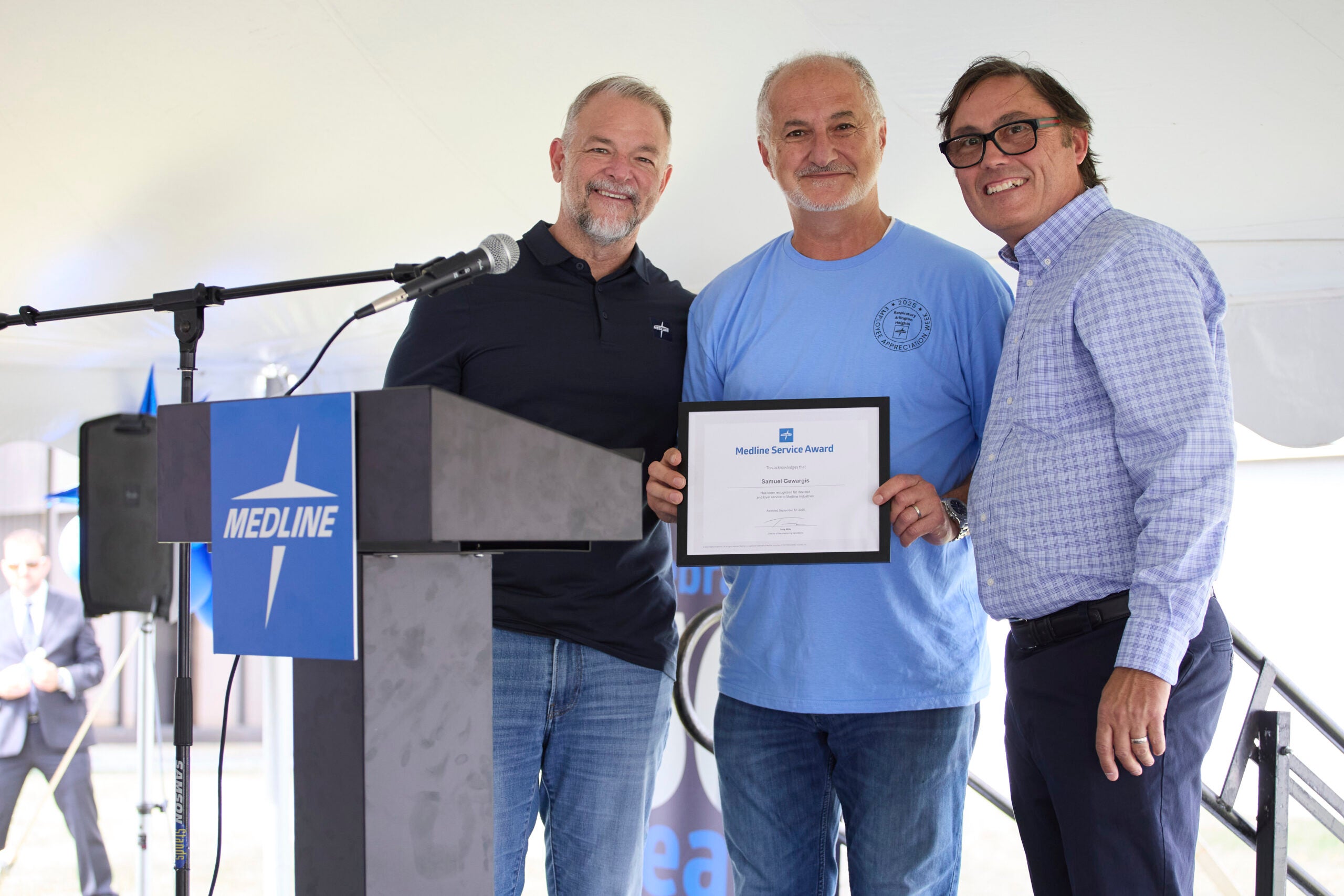 Jim Boyle and Terry Mills presenting senior buyer Samuel Gewargis with a service award at Medline’s Arlington Heights facility