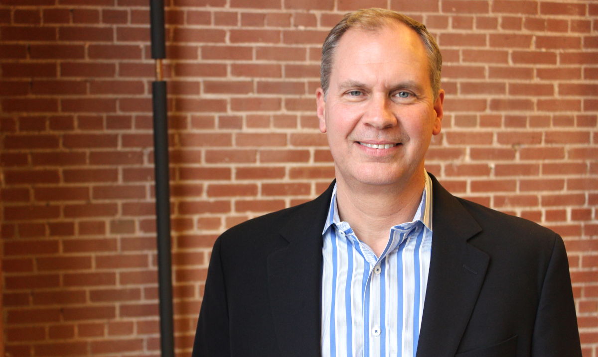 Jim Eberlin standing in front of an exposed brick wall