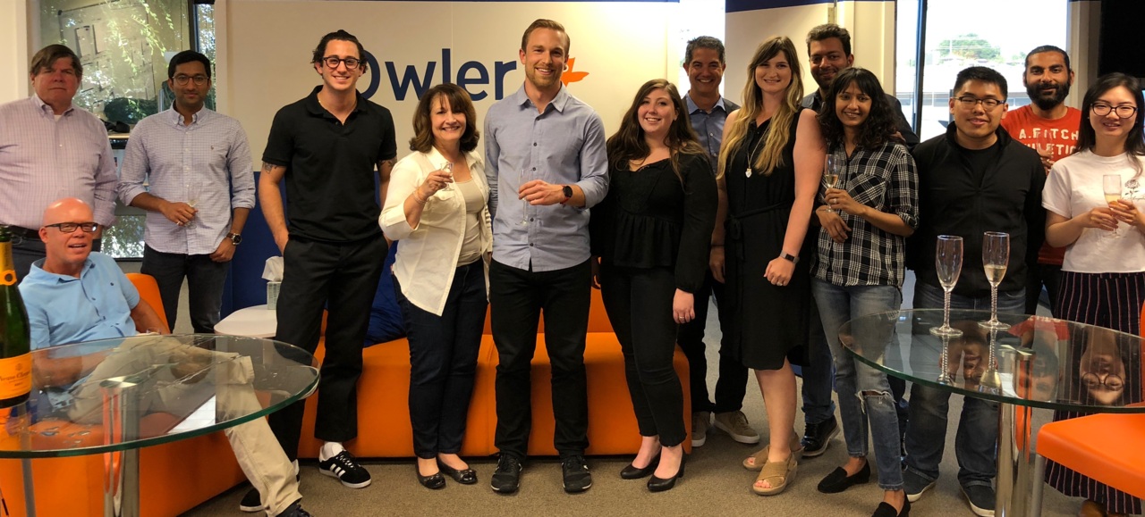 Jim Fowler seated at the left of an Owler team group photograph in the office
