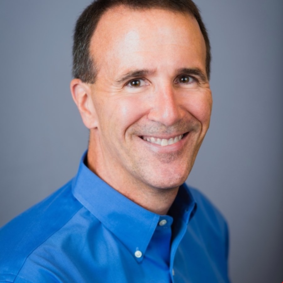 Earlier press portrait of Jim Ivers in a blue shirt against a gray background
