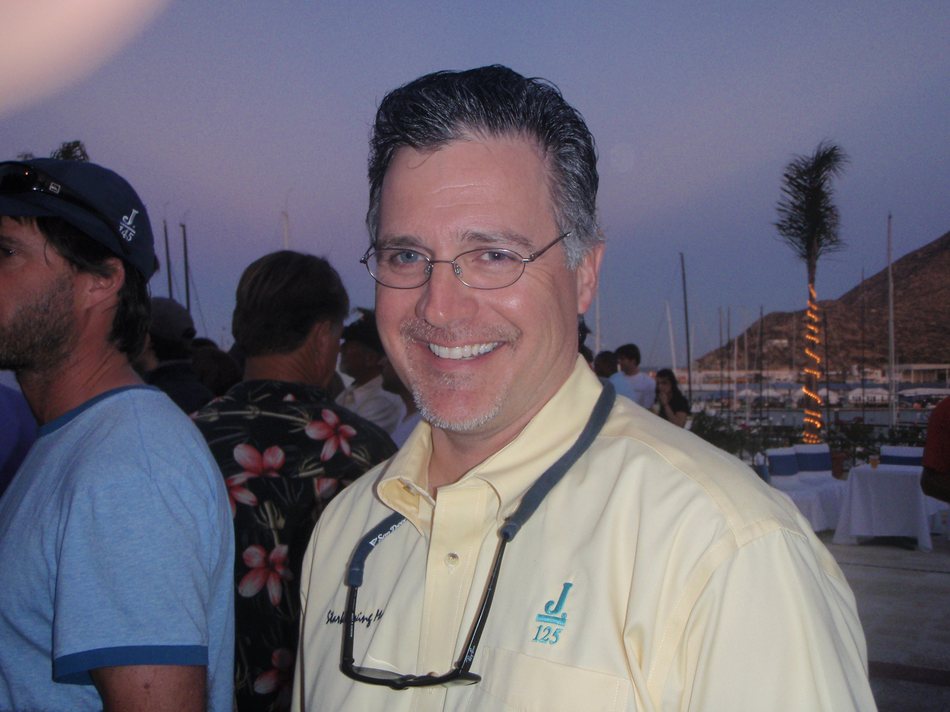 Jim Madden smiling at a sailing awards gathering, wearing a Stark Raving Mad sailing shirt