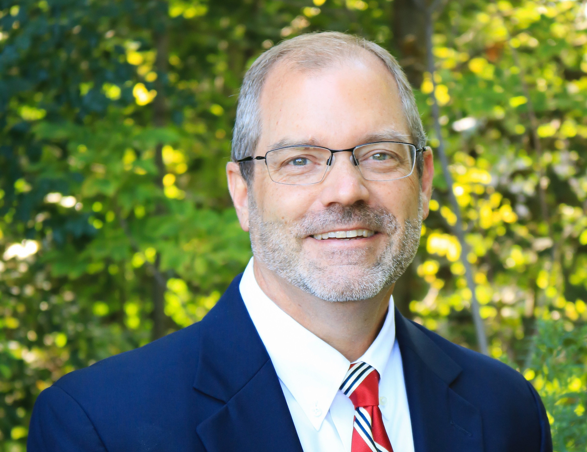 Jim McKenna outdoors in a dark jacket and striped tie