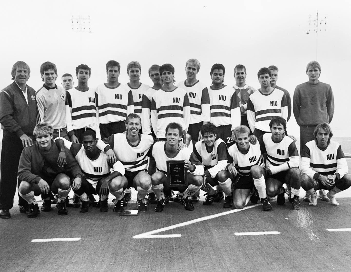 Jim Pisani holding a plaque in the front row of his Northern Illinois University soccer team