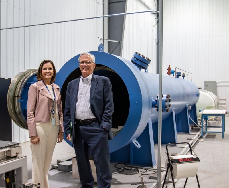 Jim Reagan and Barbara Supplee standing beside industrial equipment during an SAIC Indiana workforce visit