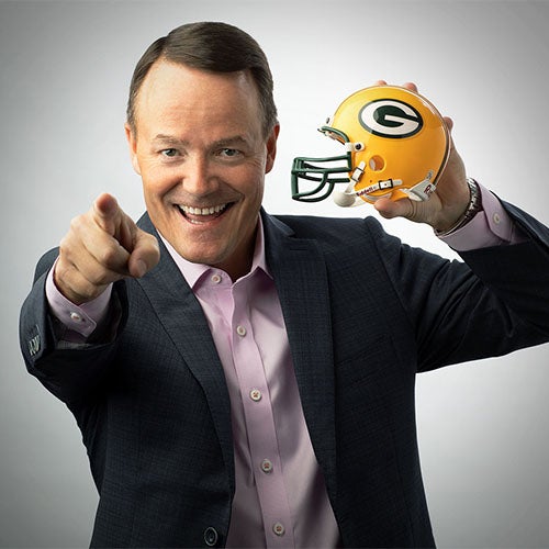 Jim Ryan holds a Green Bay Packers helmet and points toward the camera in a Flexera press photograph
