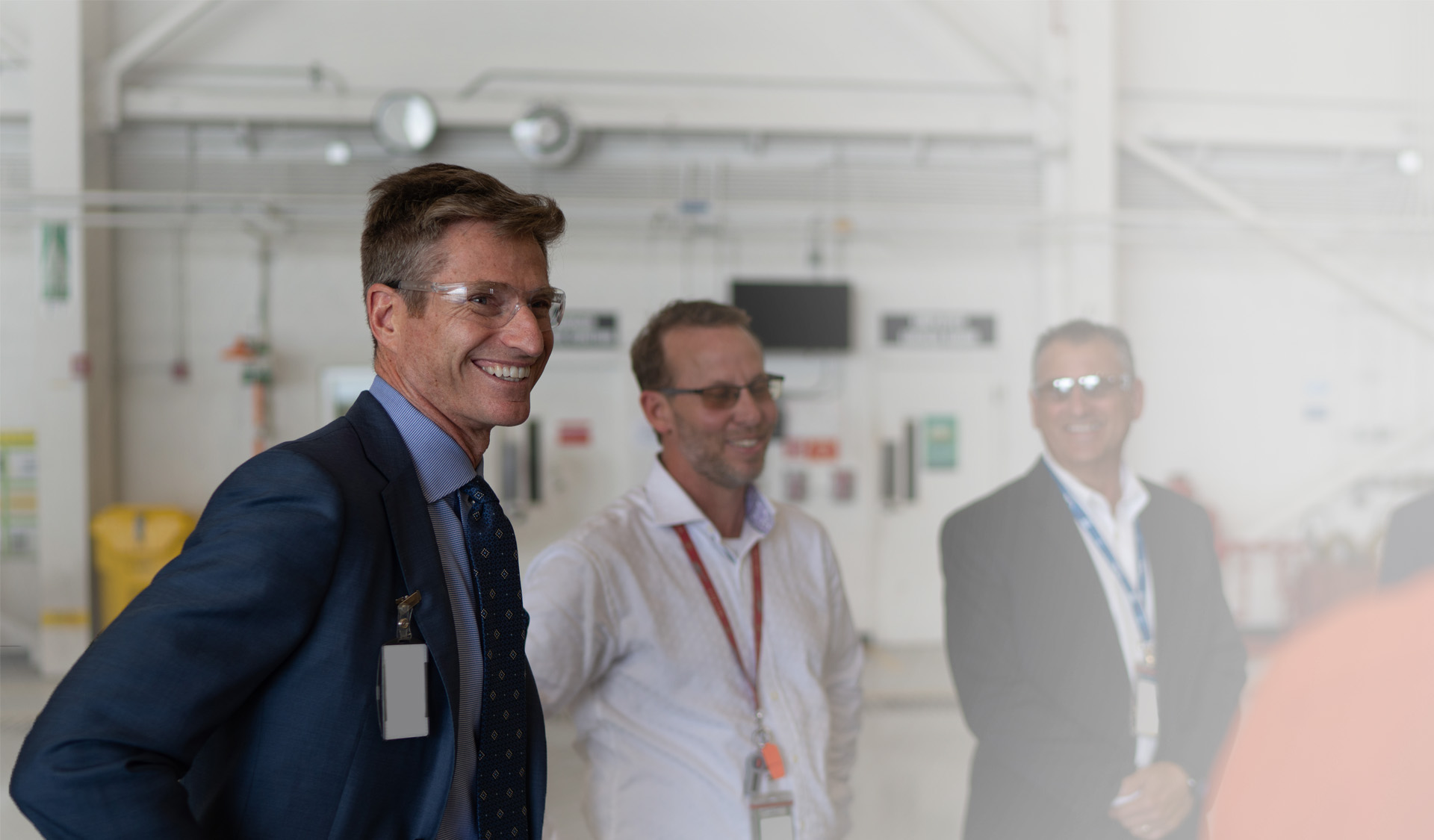 Jim Taiclet, wearing safety glasses, speaking with colleagues at a Lockheed Martin facility