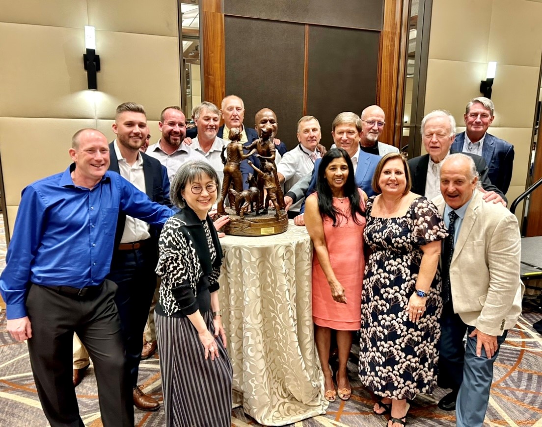 Brock and a group of colleagues gathered around an award at a ceremony