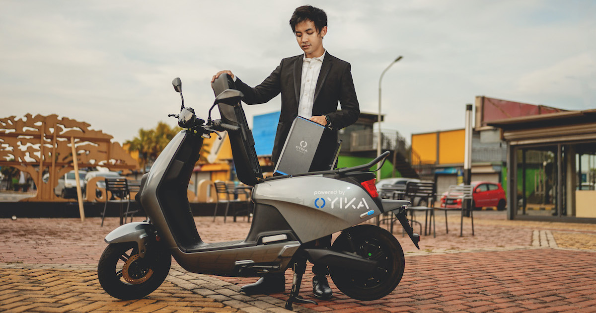 A demonstration rider lifting an Oyika battery into an electric scooter