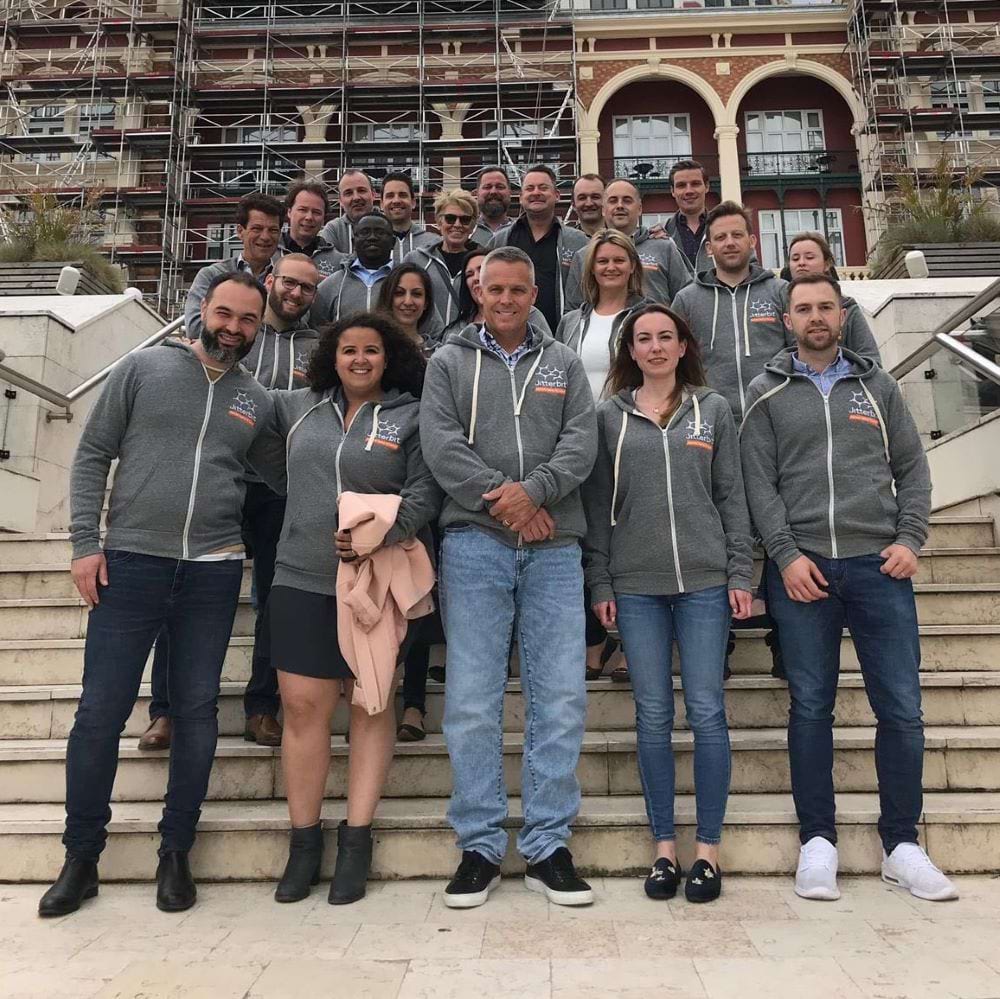Members of Jitterbit's EMEA team wearing matching gray hoodies on outdoor steps
