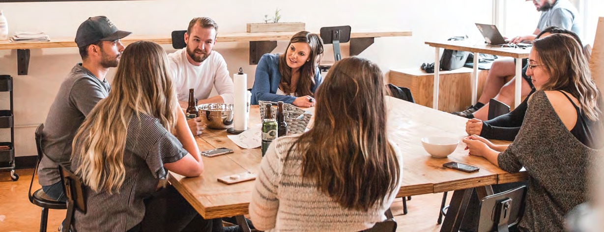 People talking around a shared table in an illustrative photograph published in Jive’s Pearson case study