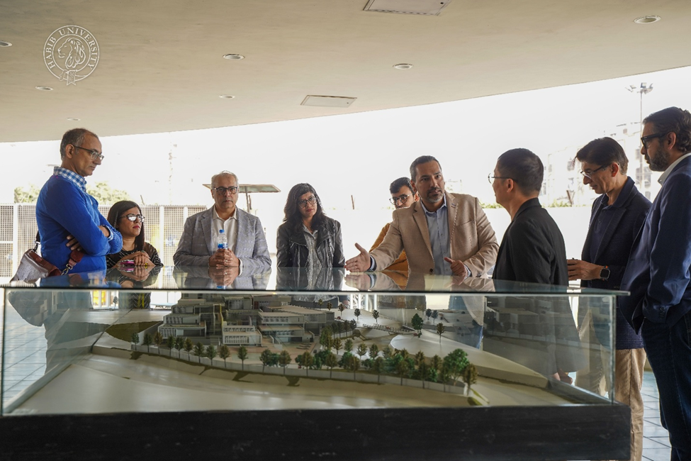 JJ Zhuang and a group of visitors gathered around a campus model at Habib University