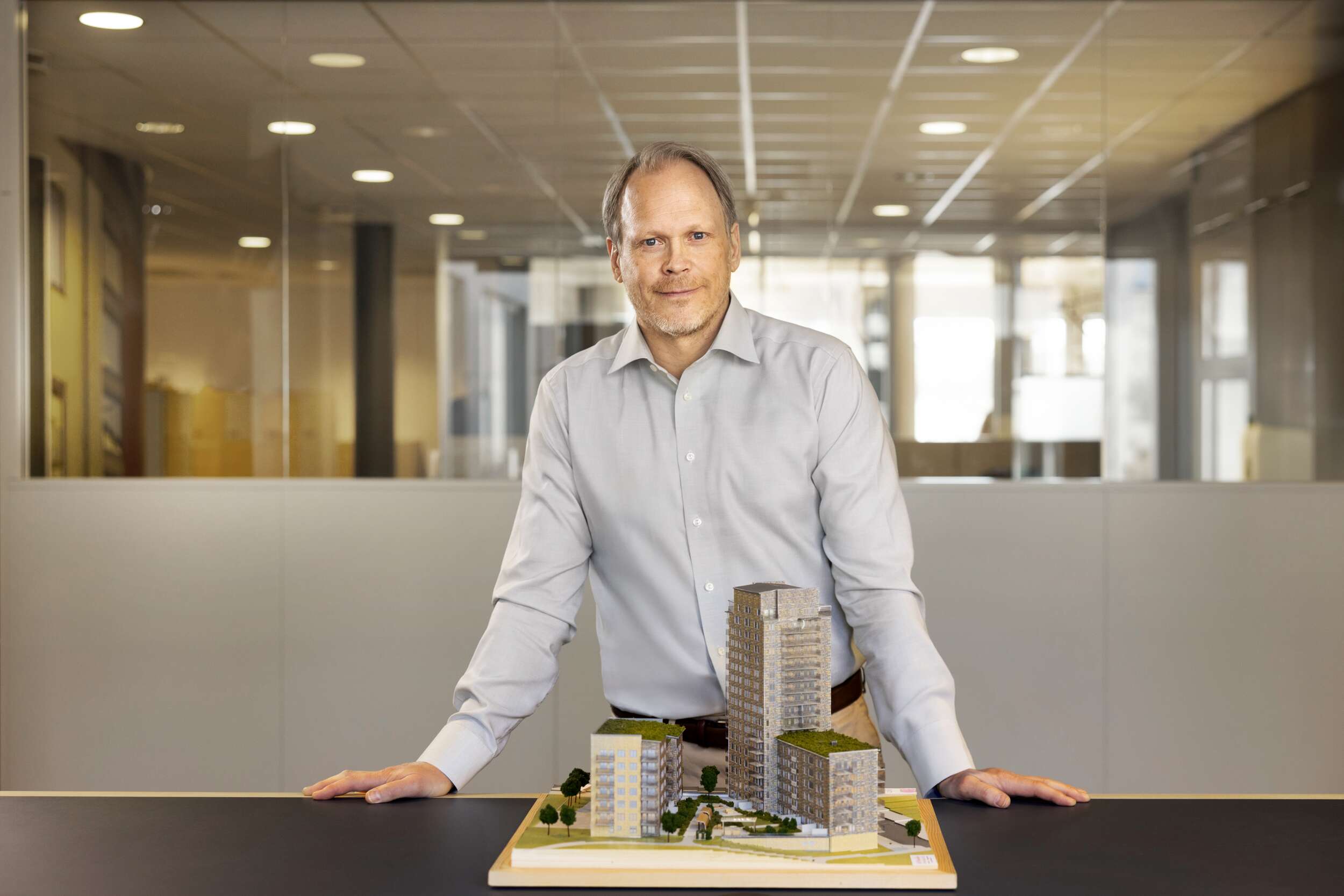 JM chief executive Mikael Åslund standing behind an architectural model