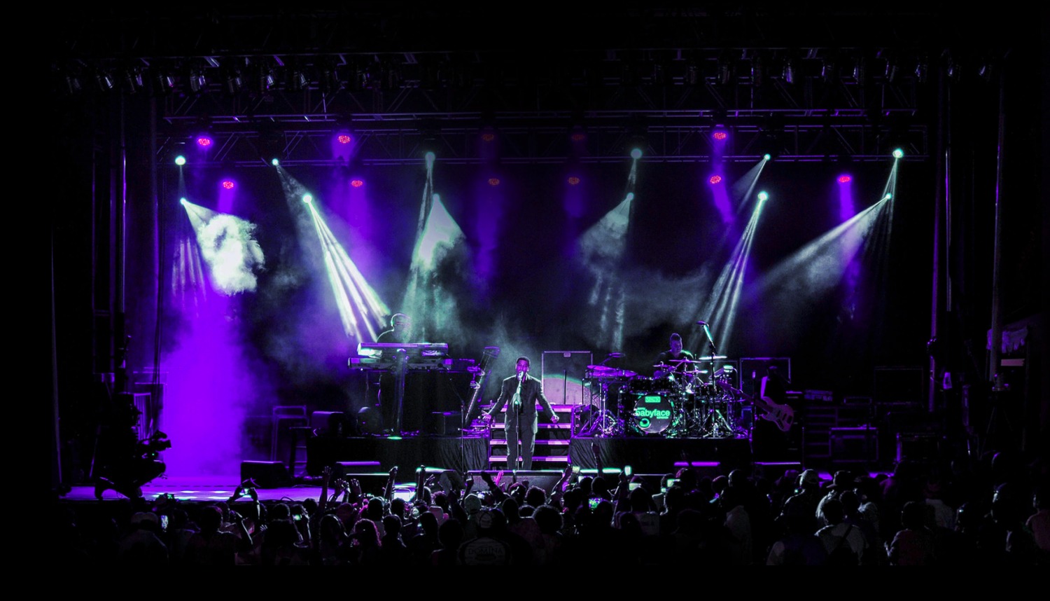 A performer and band on the brightly lit Richmond Jazz and Music Festival stage before a nighttime crowd