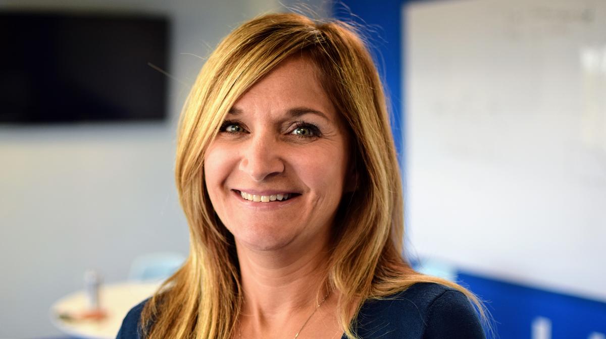 Joan Butters photographed in an office, smiling toward the camera