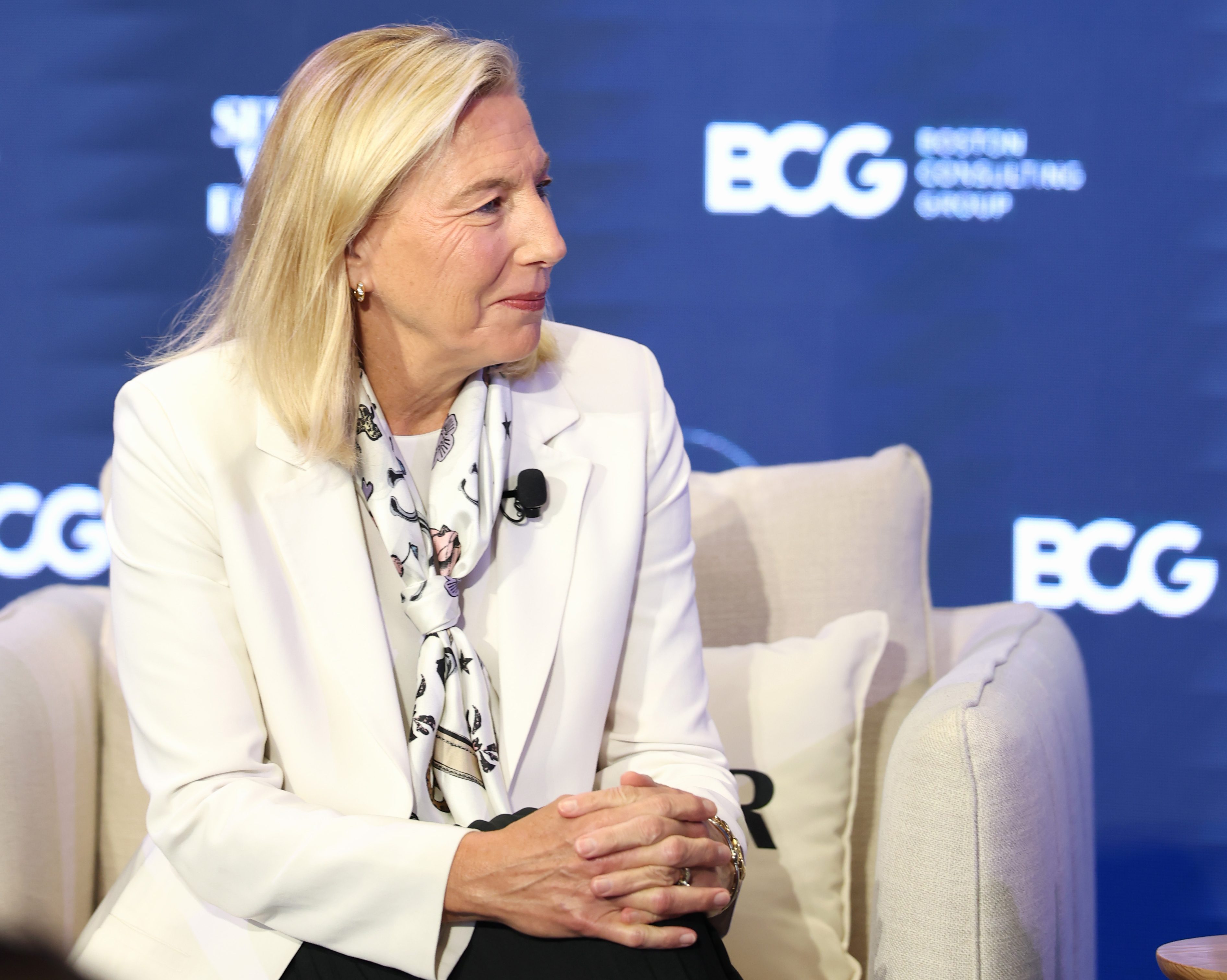 Joanne Crevoiserat in a white jacket and patterned scarf during a seated conversation at Semafor World Economy