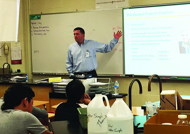 Joe Berquist gestures toward a presentation while discussing STEM careers with students in a science classroom.