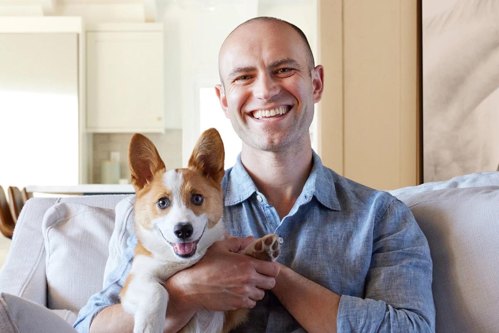 Joe Spector sitting on a sofa with his corgi Eddie
