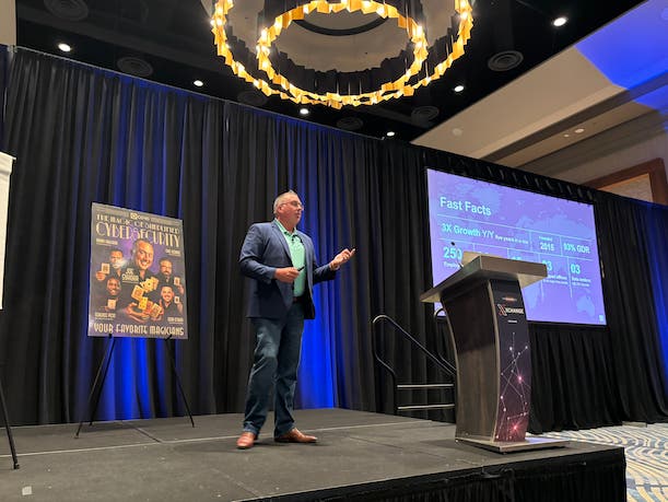 Joe Sykora speaking onstage during a cybersecurity channel event