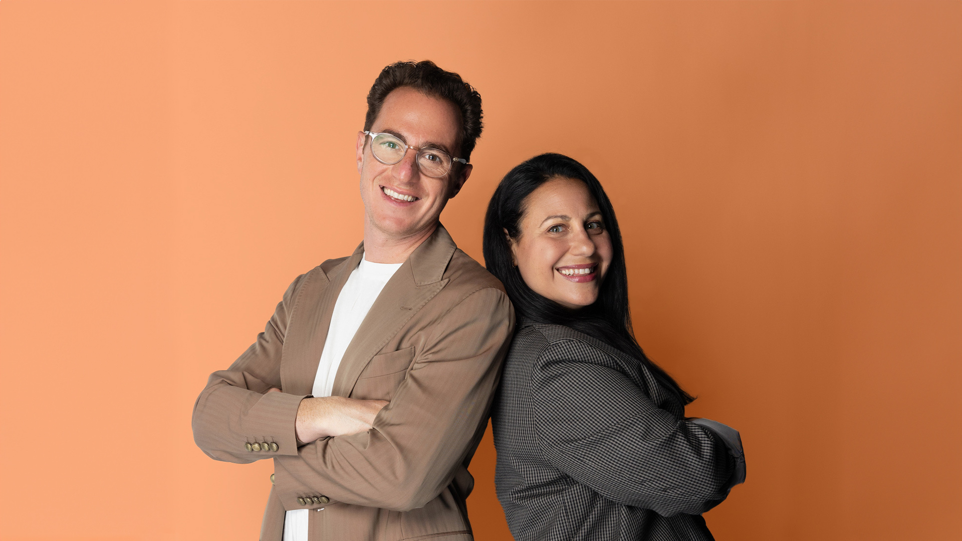 Joe Yakuel and Movado Group's Alicia Reich standing back to back against an orange background
