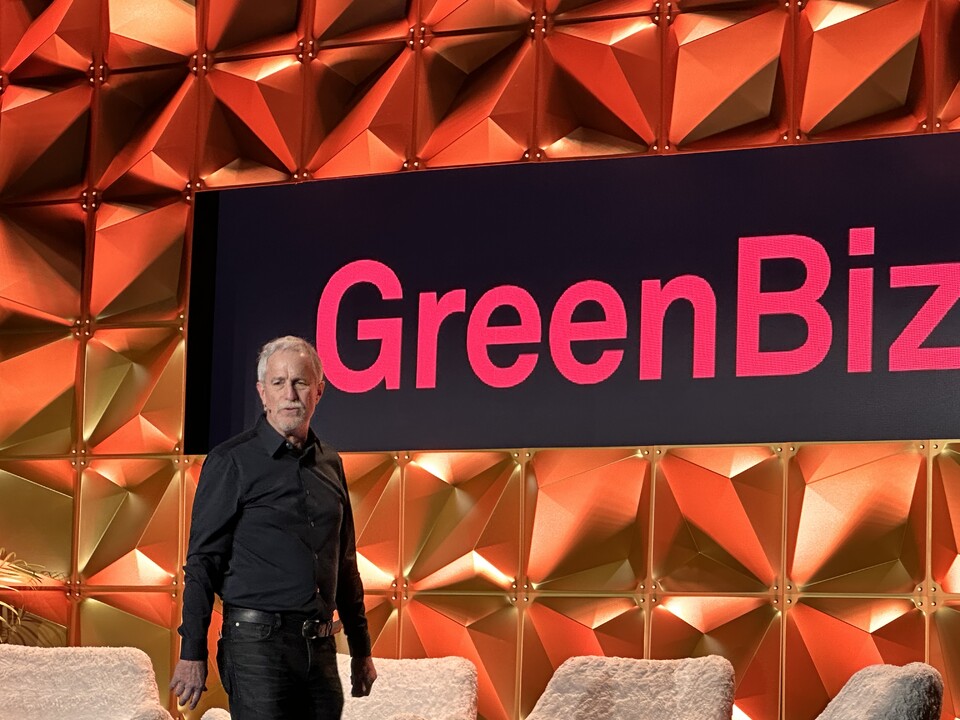 Joel Makower stands on a brightly lit GreenBiz conference stage