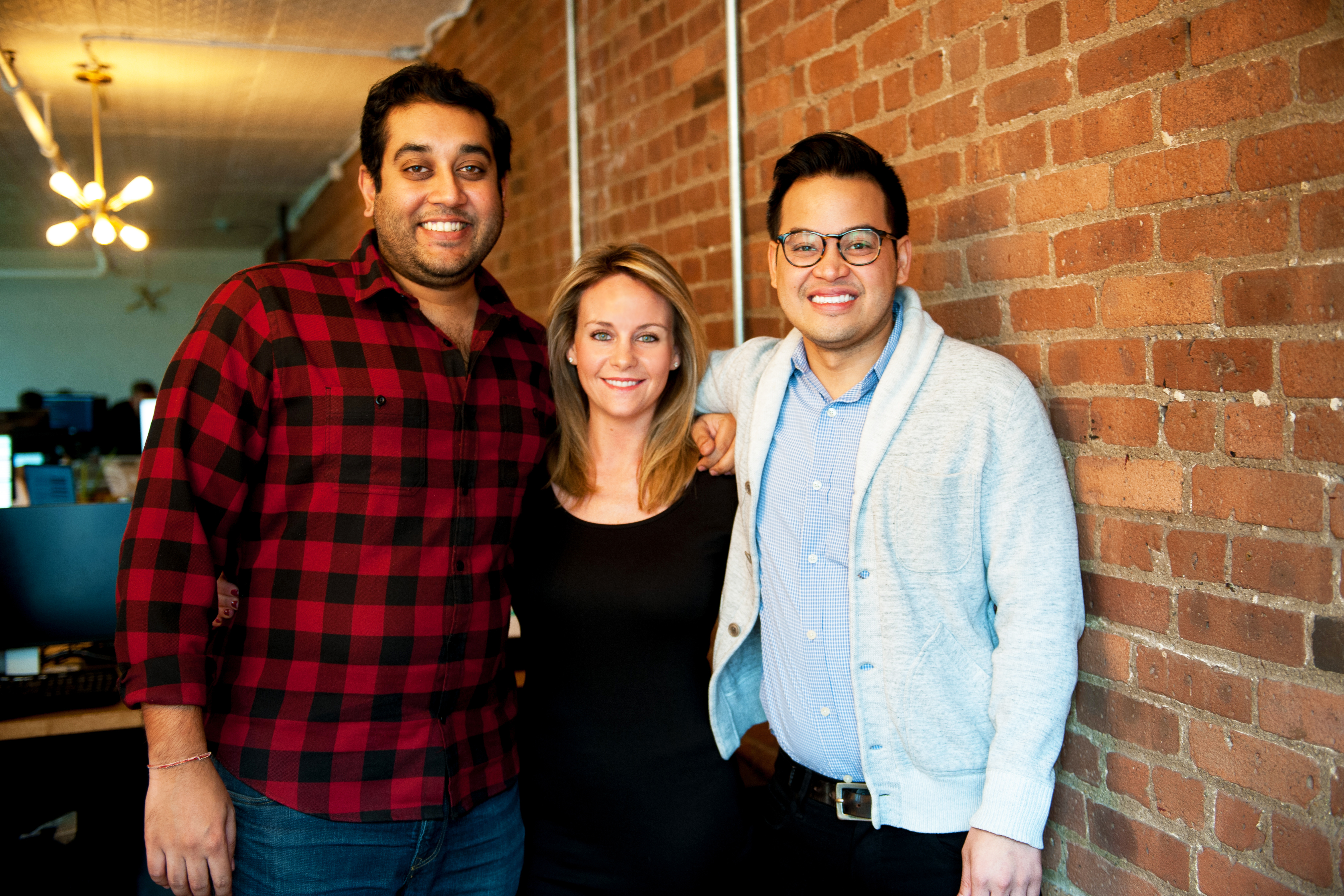 SevenRooms co-founders Kinesh Patel, Allison Page and Joel Montaniel standing together beside an exposed brick wall