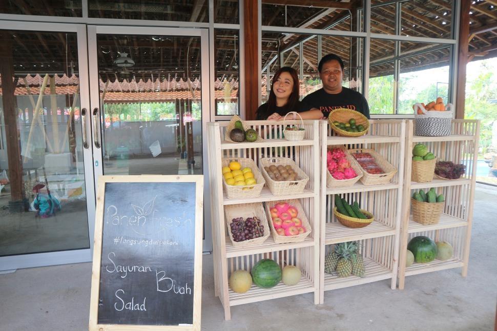 Astrid Juanita Stephanie and Johannes Dwi Cahyo Kristanto behind baskets of produce outside Panen Fresh