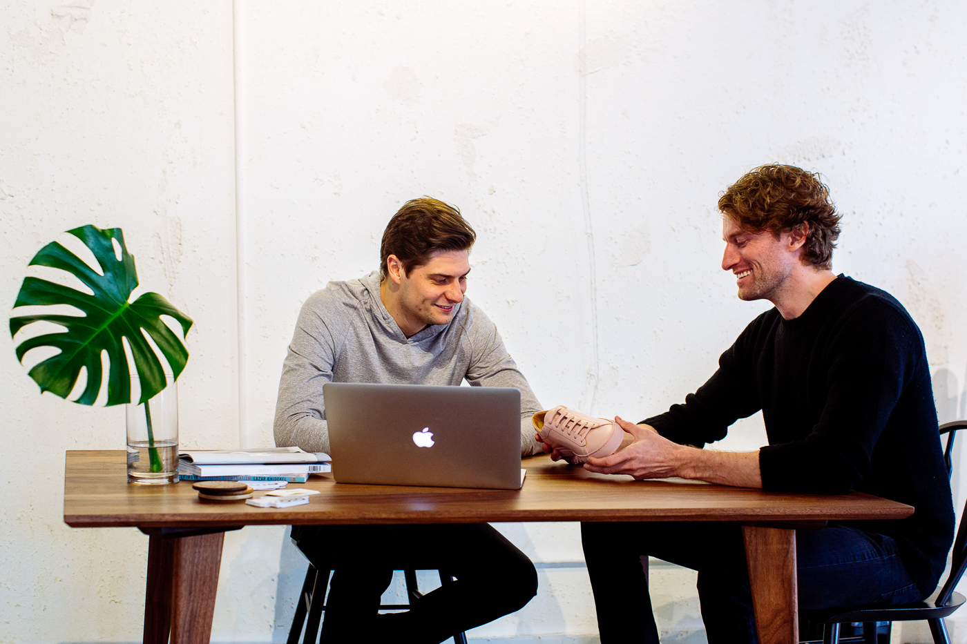 Chris Wichert at a laptop and Johannes Quodt holding a sneaker across their worktable