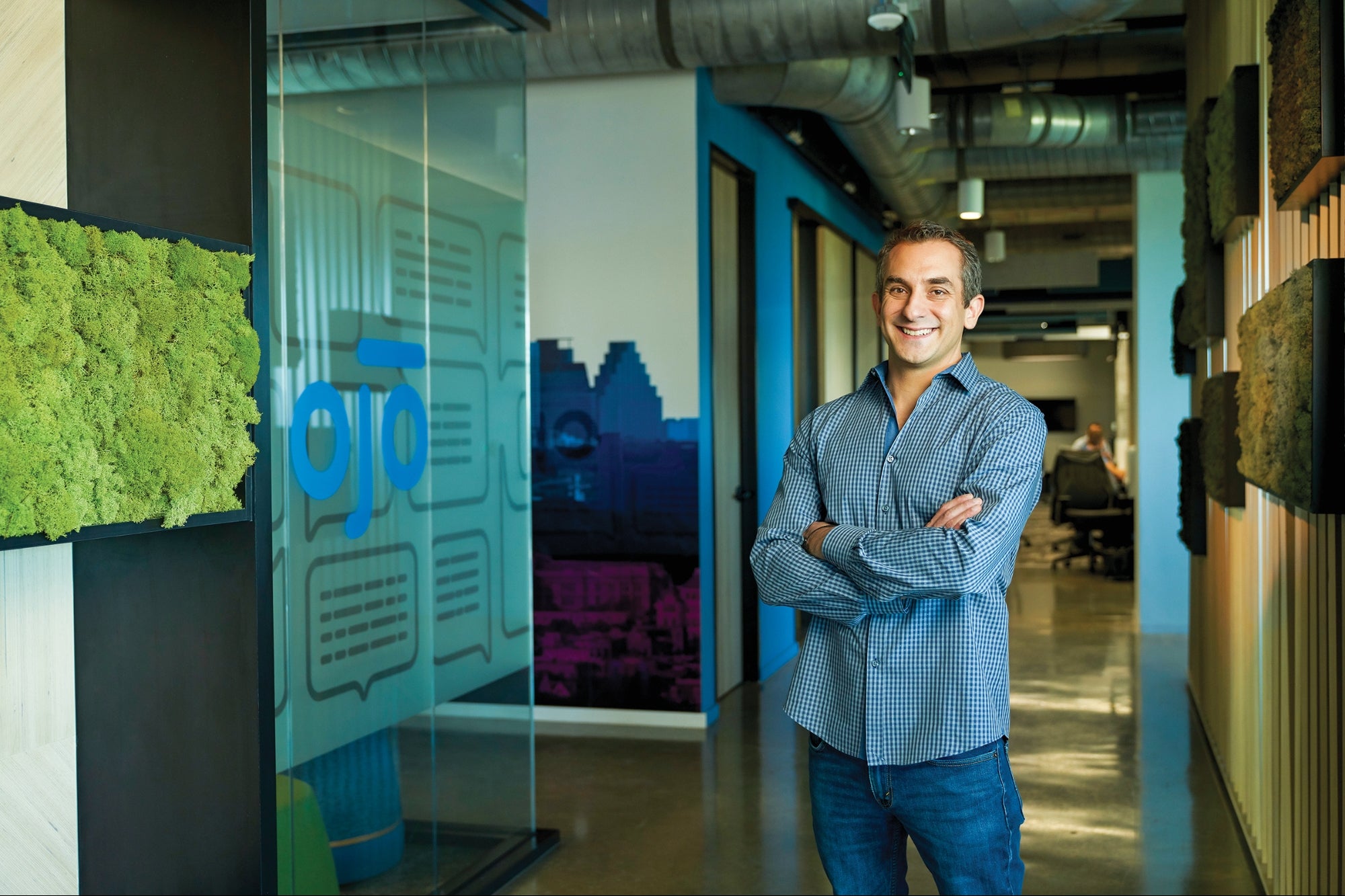 John Berkowitz standing in an OJO office corridor beside a glass wall