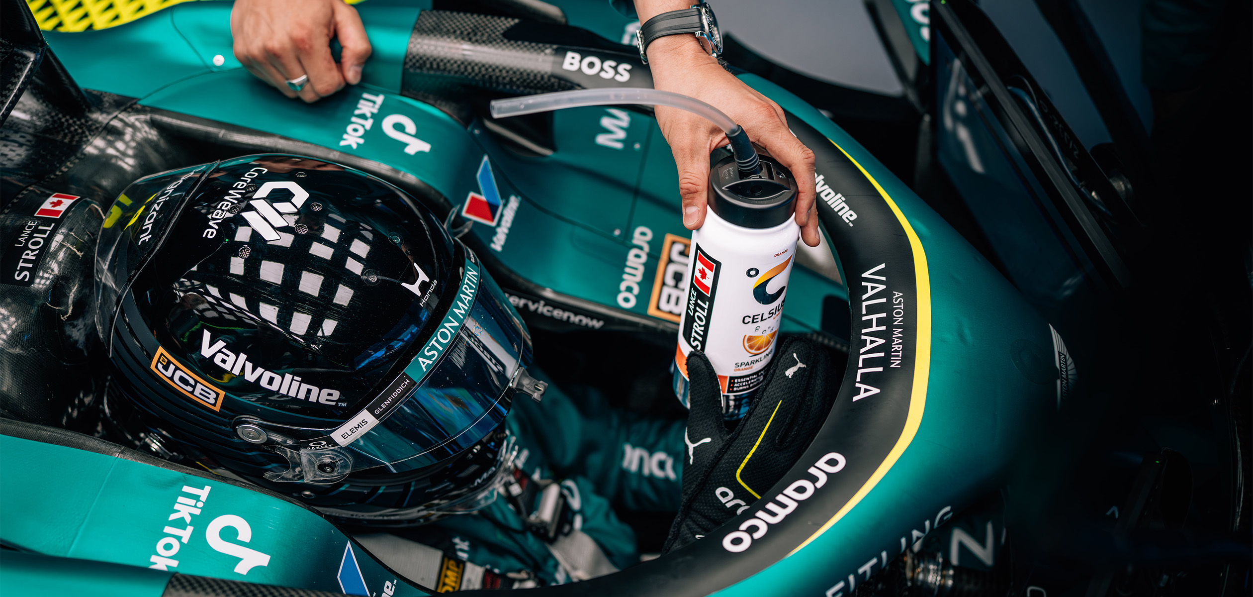 A Celsius branded bottle held above Lance Stroll’s Aston Martin Formula One cockpit