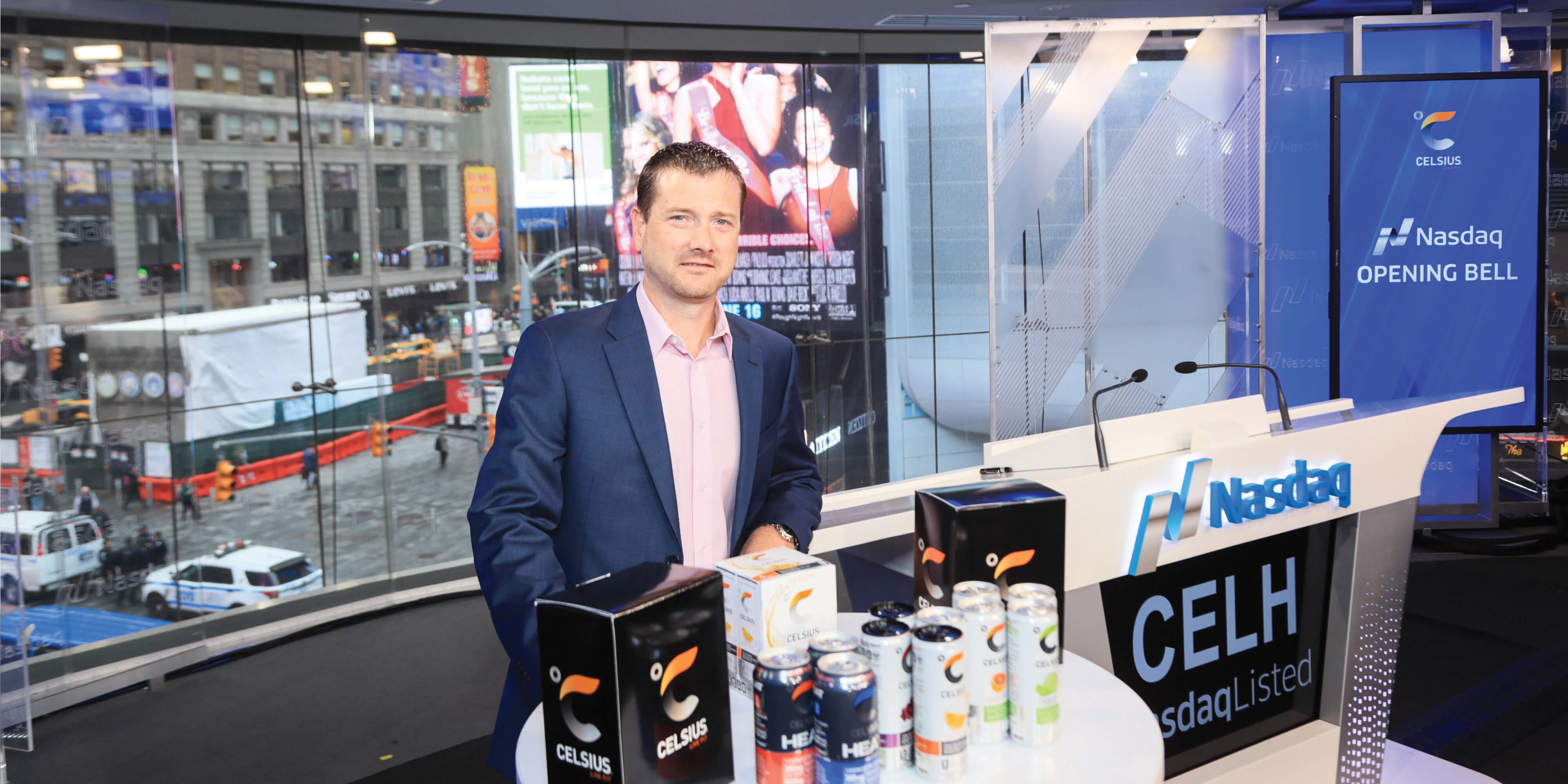 John Fieldly beside the Nasdaq opening-bell podium and a display of Celsius drinks